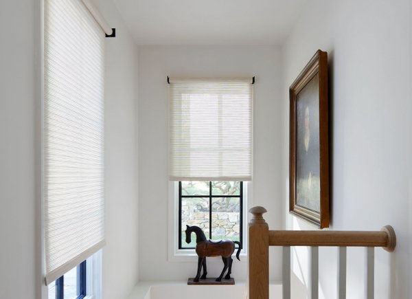 the-shade-store-woven-roller-shades-mesa-verde-sand-woven-wood-roller-shades-over-stairs-wooden-horse-statue-hero-image-2020-chappaqua-600x435